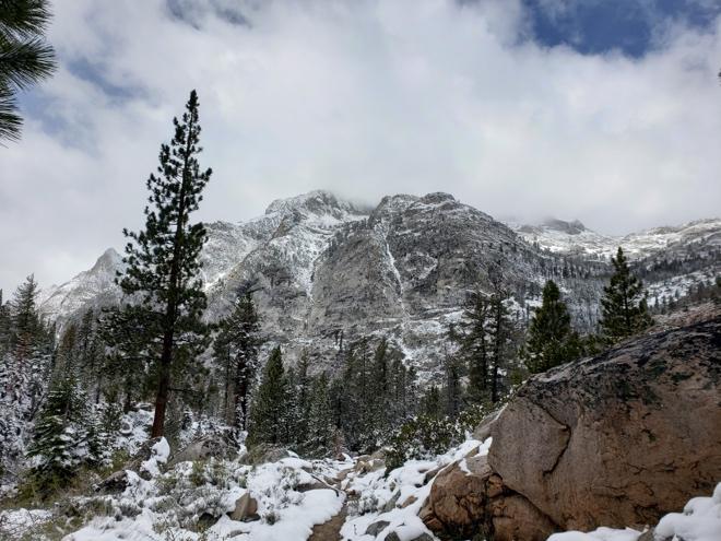 Snow-covered rocks and trees in a serene mountain landscape, showcasing winter's beauty and tranquility.