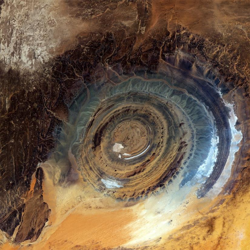 Aerial view of a circular hole in the ground, showcasing its depth and surrounding terrain.